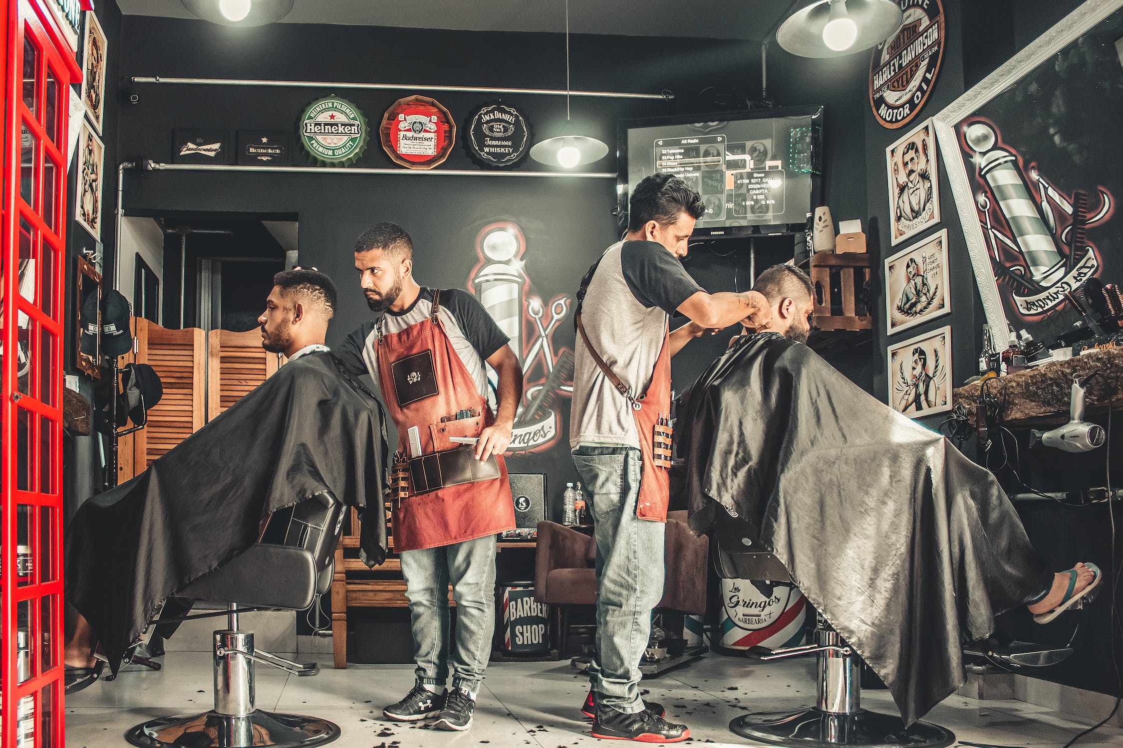 Interior image of a barbershop with two barbers cutting their customers hair