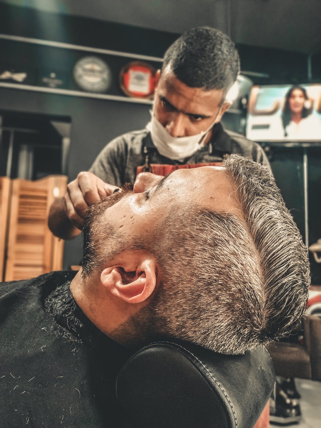 Barber trimming customers beard with electric trimmer